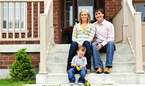 happy mother,father and child sitting on front steps of home